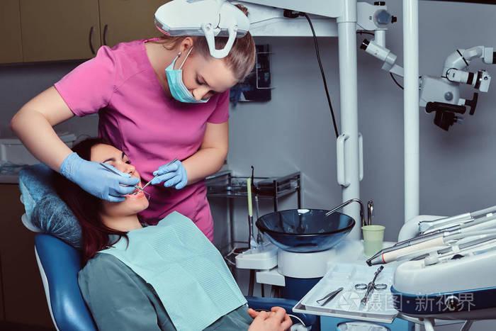 牙医正在治疗坐在诊所牙科椅上的女性病人照片-正版商用图片14asfh-摄